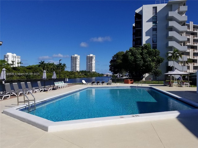 pool with a patio, fence, and a city view