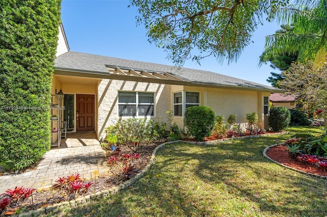 ranch-style house featuring stucco siding, a front lawn, and a shingled roof