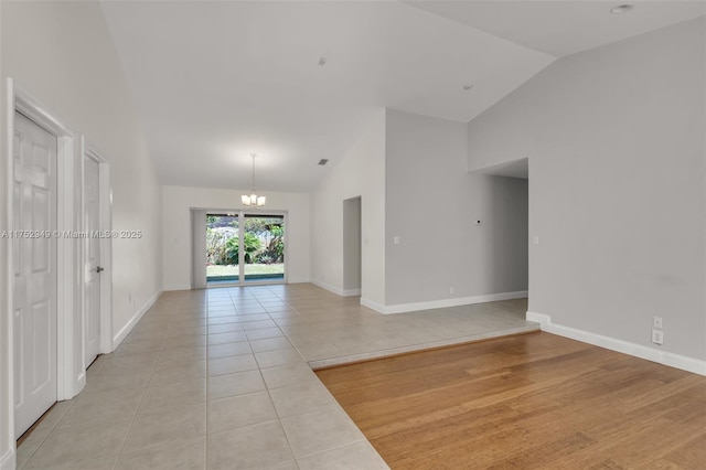 unfurnished room featuring an inviting chandelier, light tile patterned floors, and baseboards