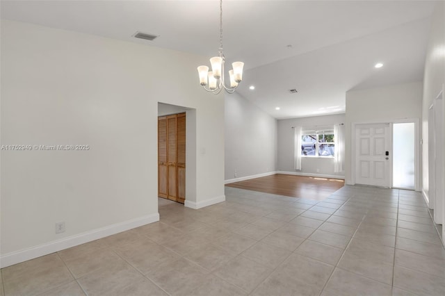 spare room featuring visible vents, baseboards, an inviting chandelier, light tile patterned flooring, and lofted ceiling