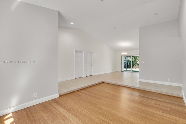 spare room featuring baseboards, recessed lighting, light wood-style floors, a notable chandelier, and high vaulted ceiling