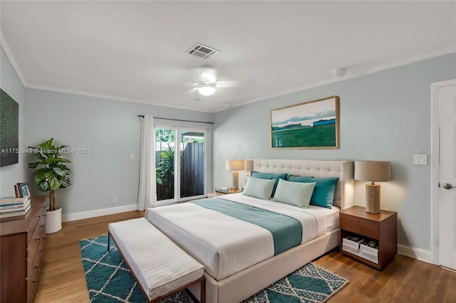 bedroom featuring visible vents, crown molding, baseboards, and wood finished floors