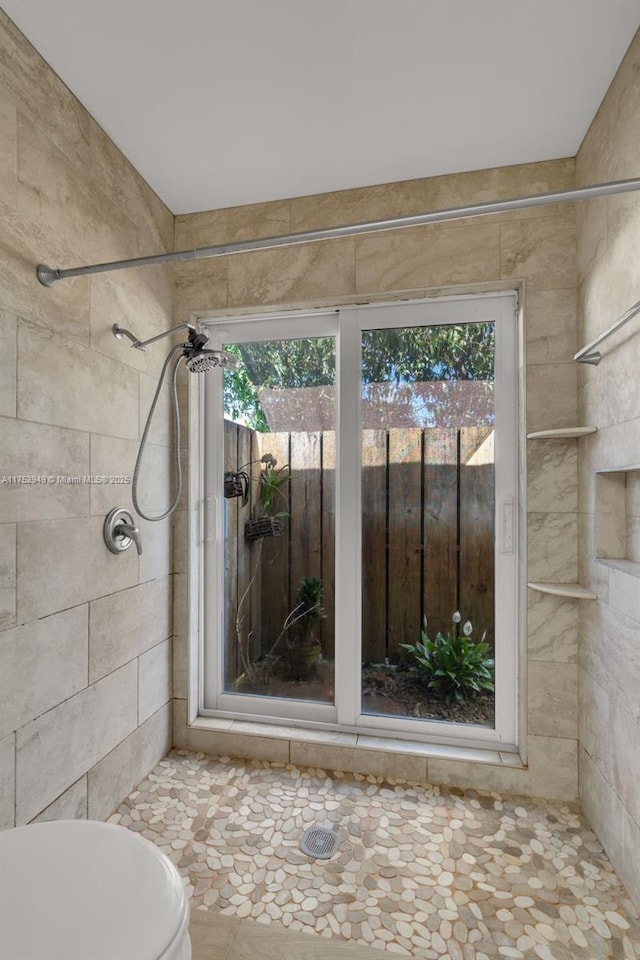 full bath featuring a tile shower, plenty of natural light, and toilet