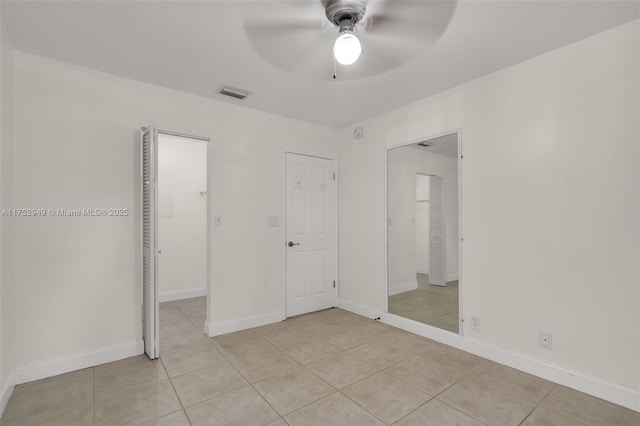 unfurnished bedroom with light tile patterned flooring, visible vents, a ceiling fan, and baseboards