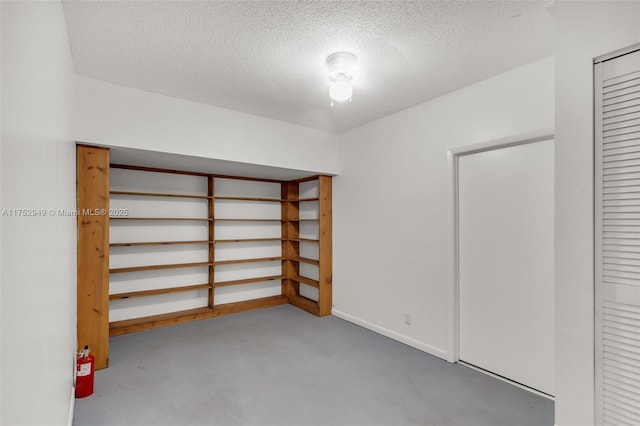 unfurnished bedroom featuring a closet, baseboards, a textured ceiling, and concrete flooring