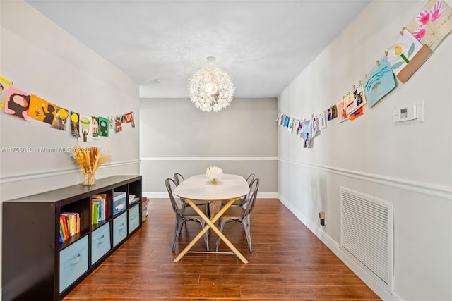 dining area with a chandelier, visible vents, baseboards, and wood finished floors