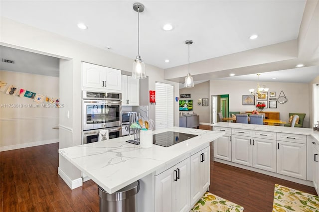 kitchen featuring a center island, black electric stovetop, dark wood-type flooring, stainless steel double oven, and white cabinets