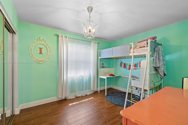 bedroom featuring a notable chandelier, baseboards, and wood finished floors