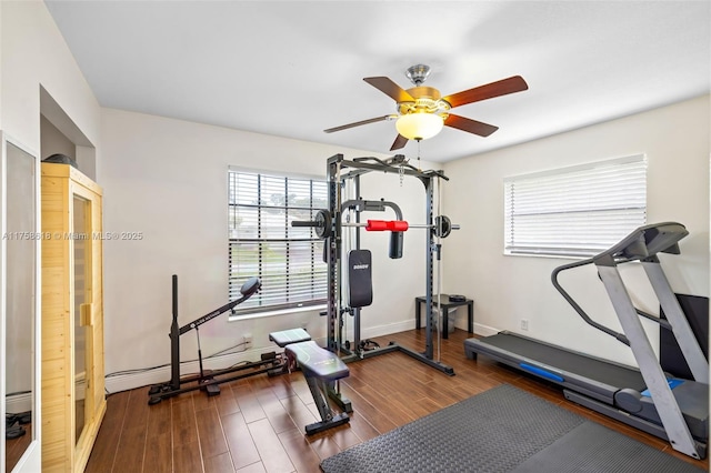 exercise room featuring wood finished floors, a ceiling fan, and baseboards