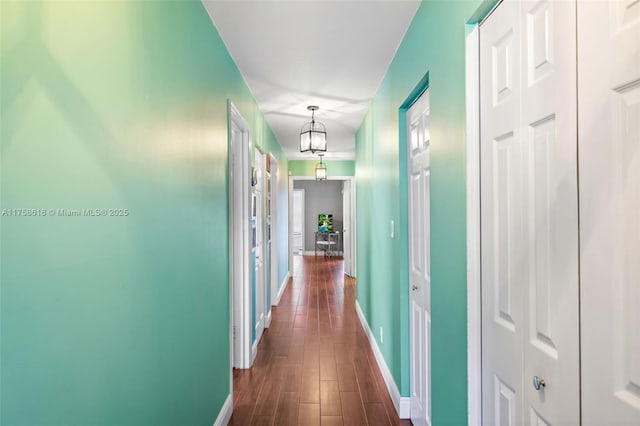 corridor featuring dark wood-type flooring and baseboards