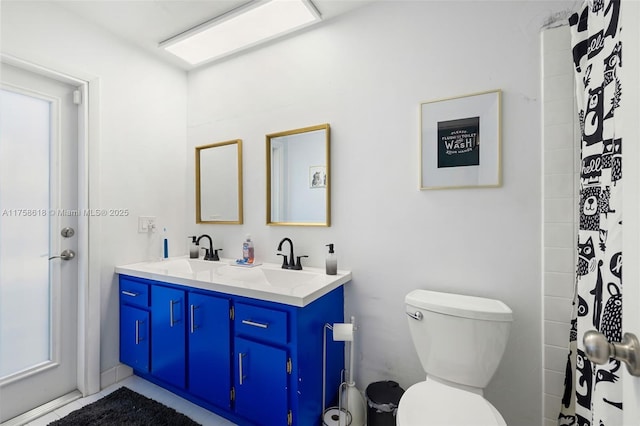 bathroom with toilet, double vanity, and a sink