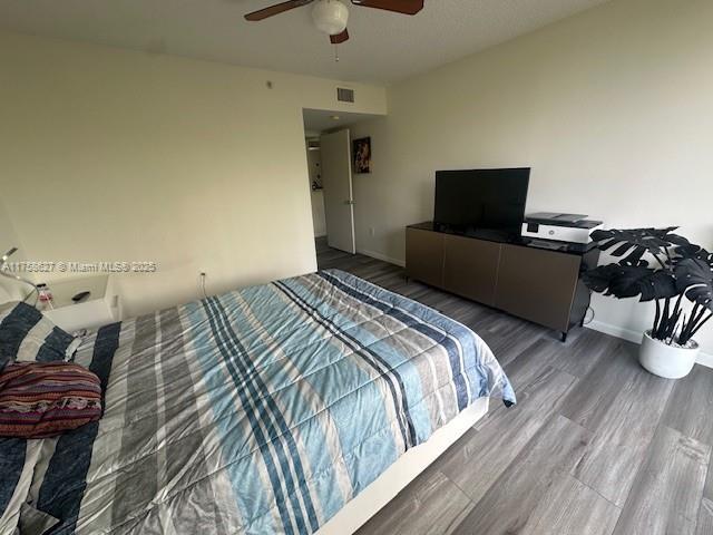 bedroom featuring ceiling fan, wood finished floors, visible vents, and baseboards