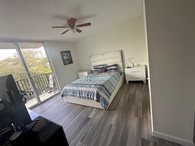 bedroom with a textured ceiling, wood finished floors, access to exterior, baseboards, and floor to ceiling windows
