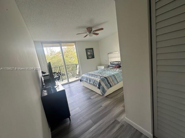 bedroom with access to exterior, a ceiling fan, a textured ceiling, wood finished floors, and a wall of windows
