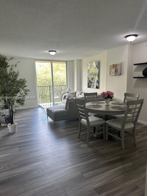 dining area with dark wood-style floors, expansive windows, a textured ceiling, and baseboards