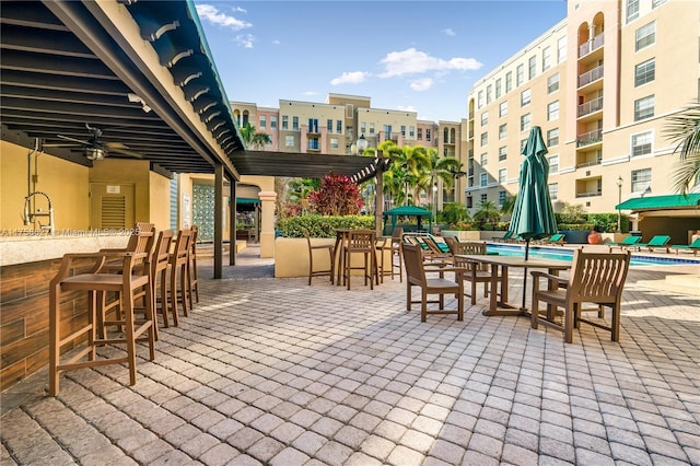 view of patio / terrace featuring a community pool, outdoor dry bar, and a sink