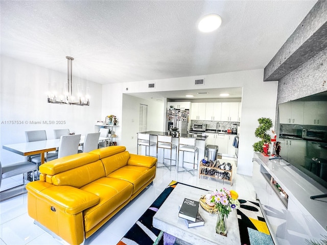 living room featuring a chandelier, visible vents, and a textured ceiling