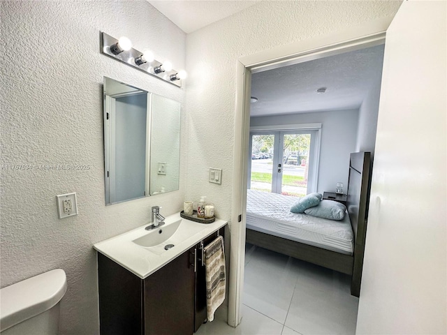 bathroom with toilet, a textured wall, and vanity