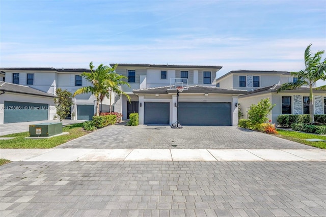 view of front of house with stucco siding, a tile roof, decorative driveway, central AC, and an attached garage