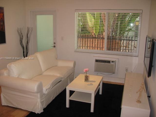 living room with an AC wall unit and wood finished floors