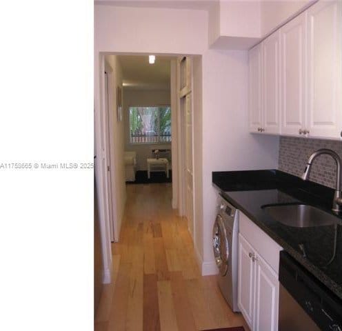 kitchen with a sink, washer / clothes dryer, white cabinets, and dishwasher