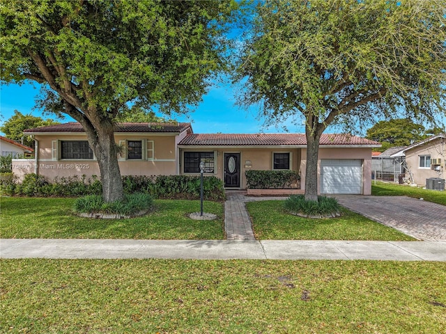 single story home with a garage, decorative driveway, a front lawn, and stucco siding