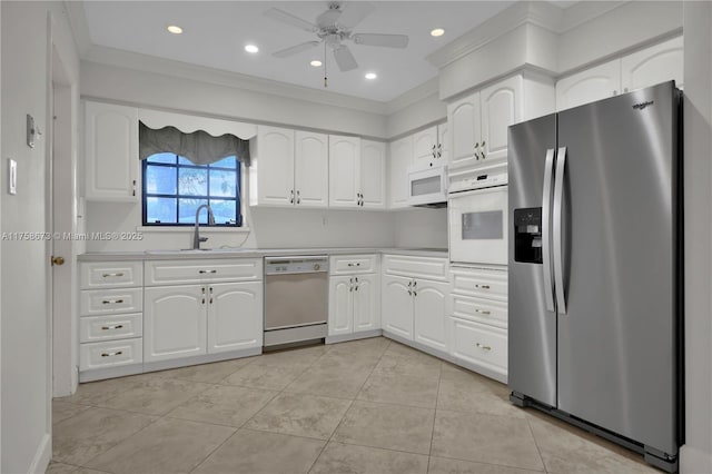 kitchen with light tile patterned floors, white appliances, a sink, white cabinets, and light countertops