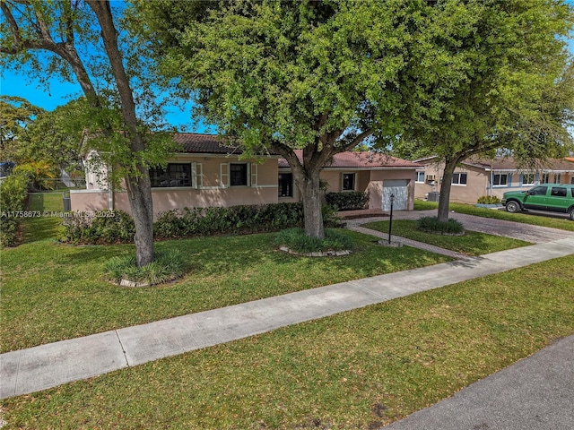 single story home featuring a garage, concrete driveway, a front yard, and stucco siding