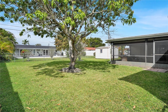 view of yard featuring an outdoor structure, a fenced backyard, and a sunroom