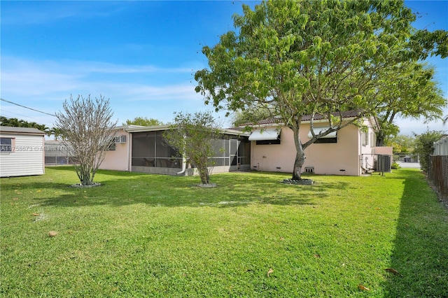 back of property with a lawn, fence, a sunroom, and stucco siding