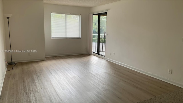 spare room with wood finished floors, baseboards, and a textured ceiling