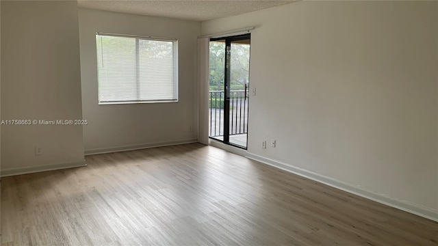 spare room featuring a textured ceiling, baseboards, and wood finished floors