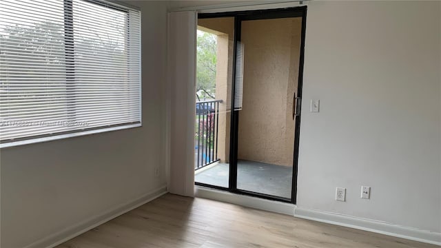 spare room with baseboards and wood finished floors