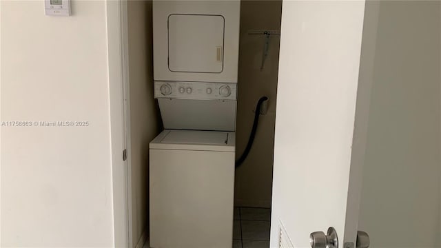 laundry area with stacked washer / drying machine, laundry area, and tile patterned flooring