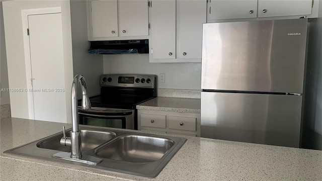 kitchen with white cabinets, stainless steel appliances, light countertops, under cabinet range hood, and a sink