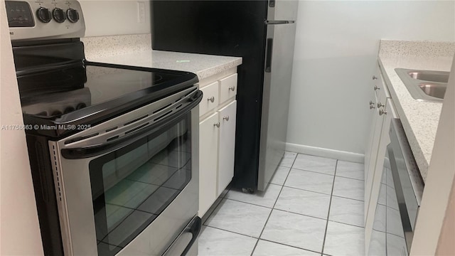 kitchen featuring stainless steel electric range oven, light tile patterned floors, light countertops, white cabinetry, and baseboards