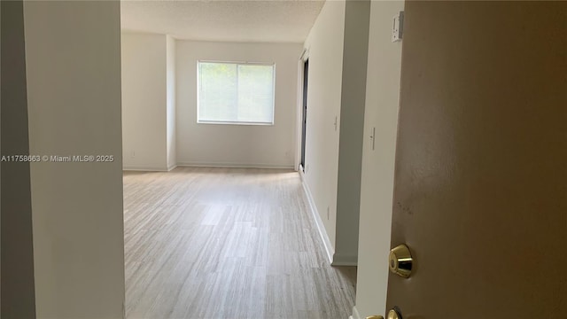 corridor with baseboards, a textured ceiling, and wood finished floors