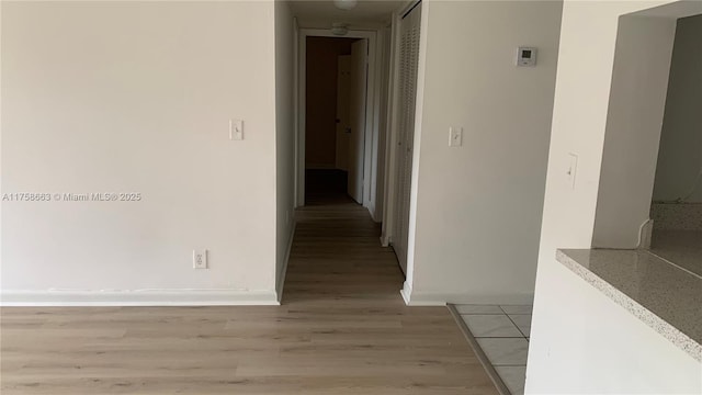 corridor featuring baseboards and light wood-style floors