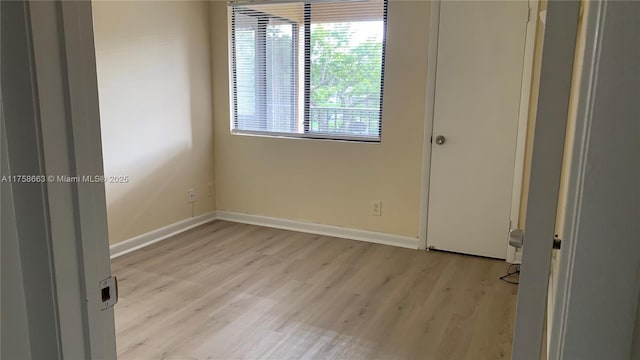 spare room with light wood-type flooring and baseboards