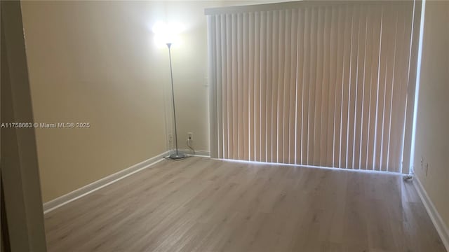 spare room featuring baseboards and wood finished floors