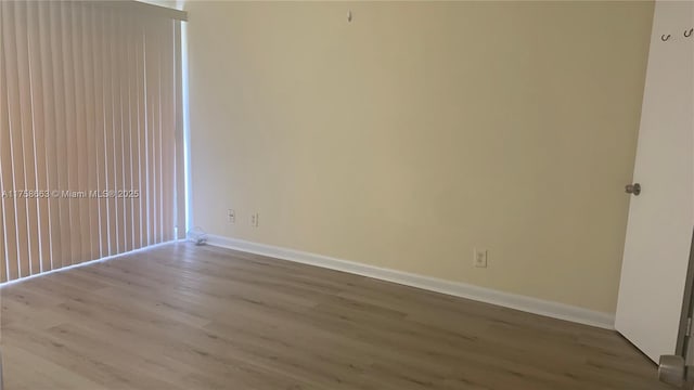 unfurnished room with baseboards and wood finished floors