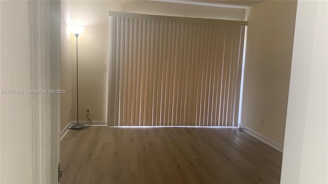 spare room featuring baseboards and wood finished floors