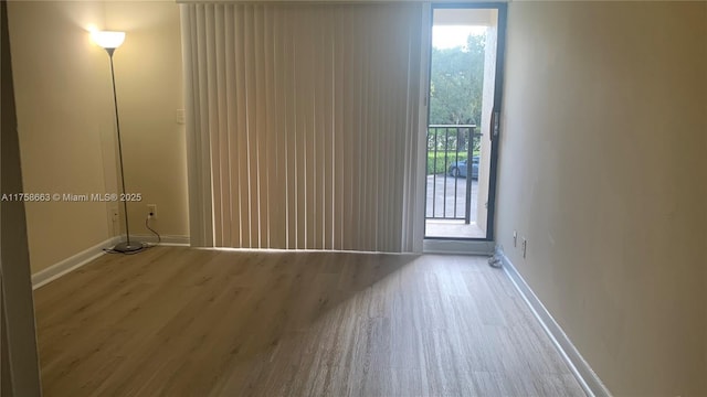 spare room featuring baseboards and wood finished floors