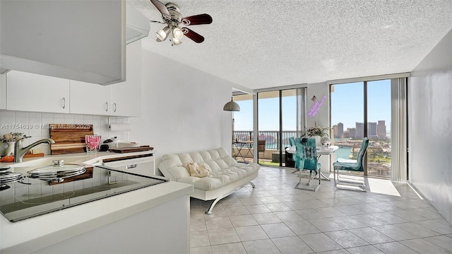 living area with light tile patterned floors, ceiling fan, a wealth of natural light, and floor to ceiling windows