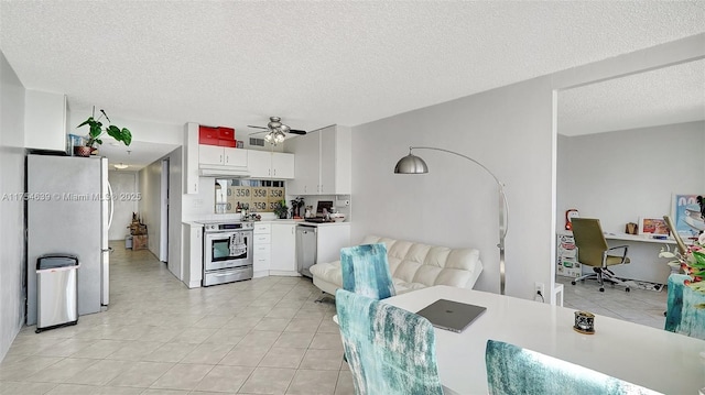 kitchen featuring light countertops, appliances with stainless steel finishes, white cabinetry, light tile patterned flooring, and under cabinet range hood