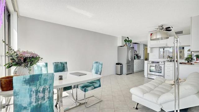 dining space with a textured ceiling, ceiling fan, light tile patterned flooring, and visible vents