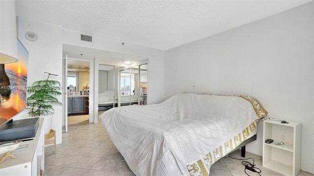 bedroom with light tile patterned floors, a textured ceiling, and visible vents