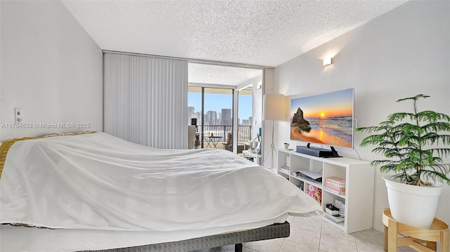 bedroom with a textured ceiling, access to outside, a wall of windows, and light tile patterned flooring