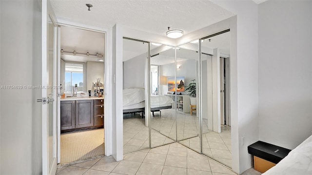 ensuite bathroom with a textured ceiling, tile patterned flooring, connected bathroom, and vanity