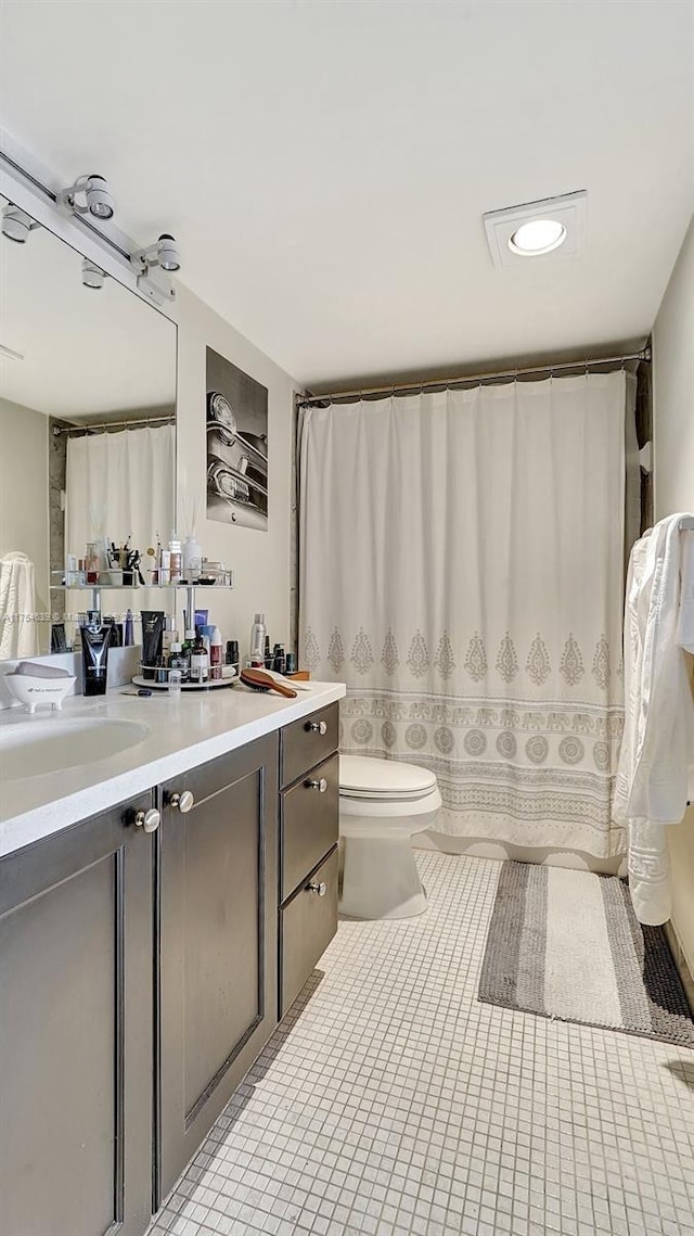 full bathroom with a shower with shower curtain, tile patterned flooring, vanity, and toilet